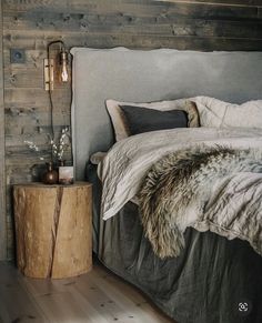 a bed sitting next to a night stand on top of a wooden floor