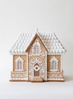 a gingerbread house with white icing on it's roof and window frames