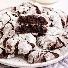 chocolate crinkle cookies on a plate with powdered sugar in the middle and one cut in half