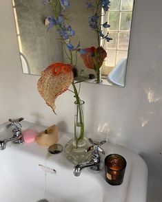 a bathroom sink with flowers in a vase on it