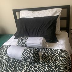 a bed with black and white sheets, pillows and blankets on top of it next to a night stand