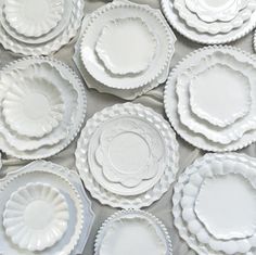 many white plates with scalloped edges are arranged on a tableclothed surface