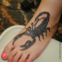 a woman's foot with a scorpion tattoo on it