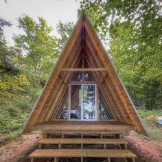 a small wooden cabin in the woods with stairs leading up to it's windows