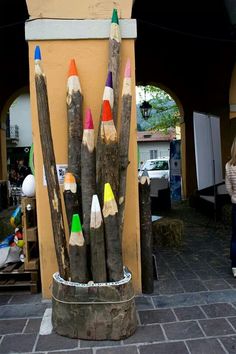 there are many colored pencils sticking out of the sticks on this pole in front of a building