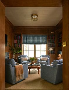 a living room filled with blue couches and wooden shelves next to a window covered in bookshelves