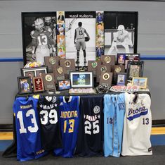 several sports jerseys are on display in front of a wall with framed pictures and memorabilia