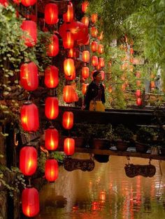 red lanterns hanging from the side of a bridge over water