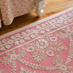 a pink rug on the floor next to a bed