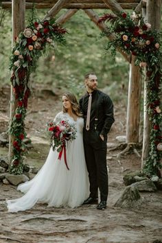 a bride and groom standing under an arch with flowers