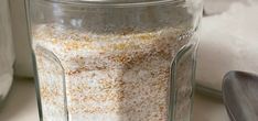 a glass jar filled with food sitting on top of a counter next to a spoon