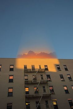 an apartment building is shown with the sun shining through the windows and clouds in the sky