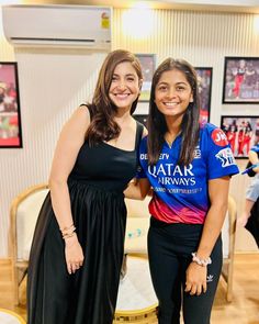 two young women standing next to each other in front of pictures on the wall behind them