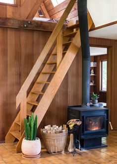 a living room with a wood burning stove and wooden stairs leading up to the loft