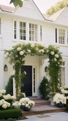 a house with white flowers and greenery on the front