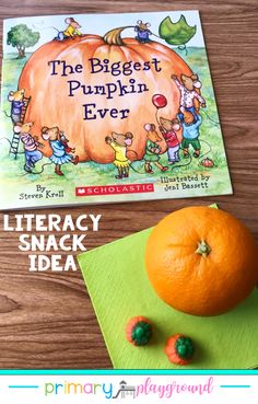 an orange sitting on top of a wooden table next to a book and two small toys