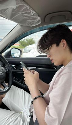 a man sitting in the driver's seat of a car using his cell phone