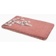 a pink towel with white flowers and leaves on the front, sitting on a white surface