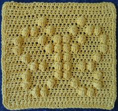 a yellow crocheted square with flowers on it