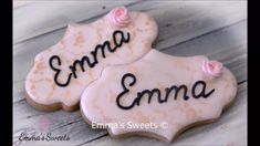 two decorated cookies with the word ema on them are sitting on a wooden table