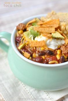 a bowl filled with chili, corn and tortilla chips on top of a napkin