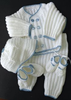 a white knitted baby outfit with blue trimmings on the collar and feet