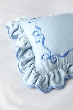 a blue pillow with ruffled edges on a white bed