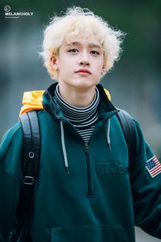 a young man with blonde hair wearing a green hoodie