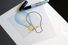 a lightbulb drawing on top of a piece of paper next to a marker