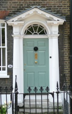 a blue front door on a brick building with wrought iron railings and white trim