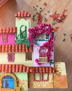 a paper model of a house with flowers on the roof