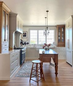 a large kitchen with an island in the middle and two stools next to it