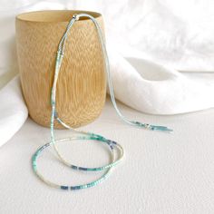 A dainty silk necklace with beige, aqua, sea green and dusky blue coloured  tiny glass beads with silver accent beads on a pale blue silk cord. Reflecting the colours of the golden sandy beaches and the beautiful aquas and blues of the gorgeous bays in St. Ives, Cornwall. This necklace measures 26in at it's longest (pulls on over the head) and has a sterling silver sliding bead so you can shorten it to 16in. (The photo of the model shows the same style necklace at it's shortest length in different colours and is for size reference only). Comes displayed in one of our pretty gift boxes, so fantastic as a present for a friend or to yourself! Shipping Uk: 2-3 days - Royal Mail 48hr tracked International standard delivery: 6- 14 days (delays can occur especially in busy periods) Please be awar Minimalist Blue Beads For Gift, Adjustable Turquoise Necklaces With Tiny Beads, Adjustable Lariat Necklace With Tiny Beads, Adjustable Tiny Beads Lariat Necklace, Adjustable Blue Lariat Beaded Necklaces, Adjustable Light Blue Necklaces With Tiny Beads, Blue Adjustable Cord Necklace For Beach, Blue Necklaces With Adjustable Cord, Blue Necklaces With Adjustable Length For Beach