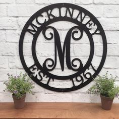 a metal sign with the letter m on it and two potted plants next to it