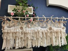 lace and flowers are hanging on the clothes line in front of a wall with blue walls