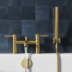 two brass faucets are connected to the wall above a bathtub with water running from it