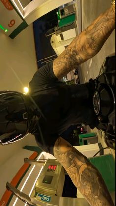 a man with tattoos on his arms and legs standing in front of a mirror wearing a black t - shirt