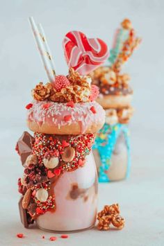 two jars filled with donuts and candy on top of each other next to some candies