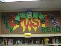 a book shelf with books on it and a giant green monster in the middle reading