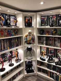 a room filled with lots of different types of action figures and bookshelves on top of white shelves