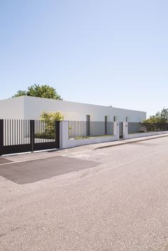 an empty street with a white building and black gate