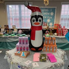 a penguin statue sitting on top of a table next to candy bars and candies