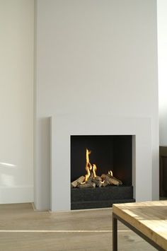 a living room with a fire place in the center and a coffee table next to it