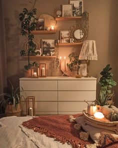 a bedroom with candles, plants and pictures on the wall