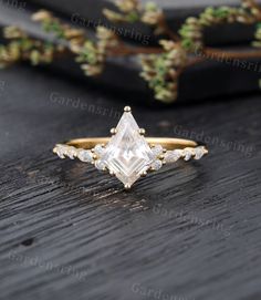 an engagement ring with a princess cut diamond surrounded by small white diamonds on a wooden table