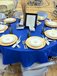 a blue table cloth topped with plates and silverware next to a framed picture frame