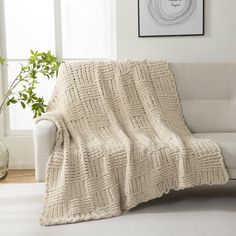 a white couch with a blanket on top of it next to a potted plant