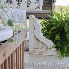 a wooden bench sitting on top of a white rug next to a planter filled with green plants