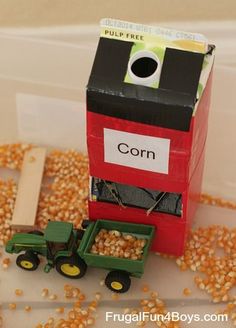 a box that has corn in it and a toy tractor on the ground next to it