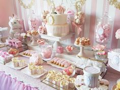 a pink and white dessert table filled with sweets